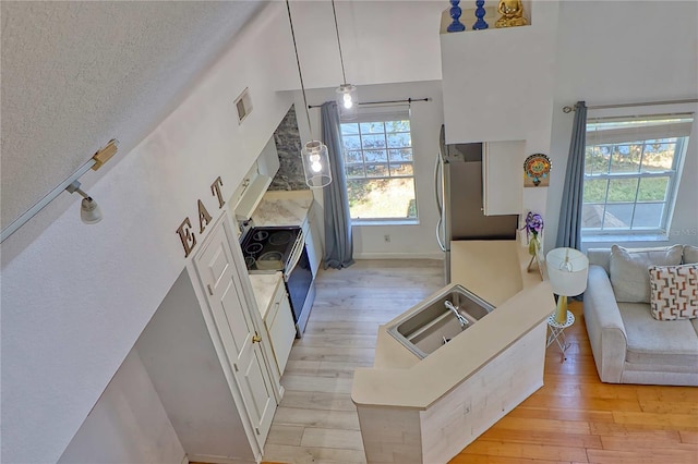 living room with sink, a high ceiling, a textured ceiling, and light wood-type flooring