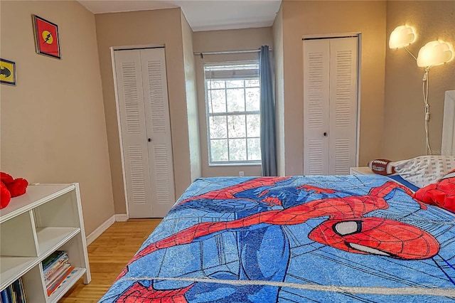 bedroom with multiple closets and wood-type flooring