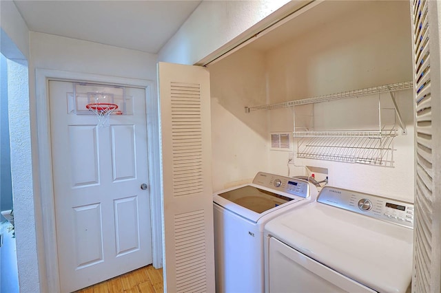 clothes washing area with washing machine and dryer and light hardwood / wood-style flooring