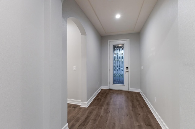 doorway to outside featuring dark wood-style floors, arched walkways, and baseboards