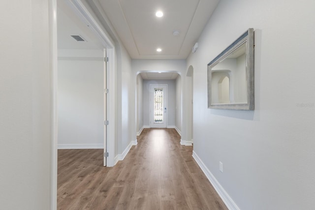 entryway featuring arched walkways, light wood finished floors, visible vents, and baseboards