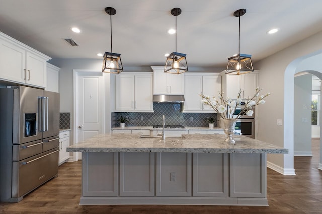 kitchen with arched walkways, pendant lighting, visible vents, white cabinets, and high end refrigerator