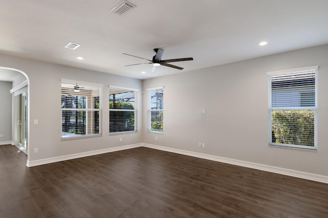 spare room featuring a ceiling fan, visible vents, dark wood finished floors, and a wealth of natural light