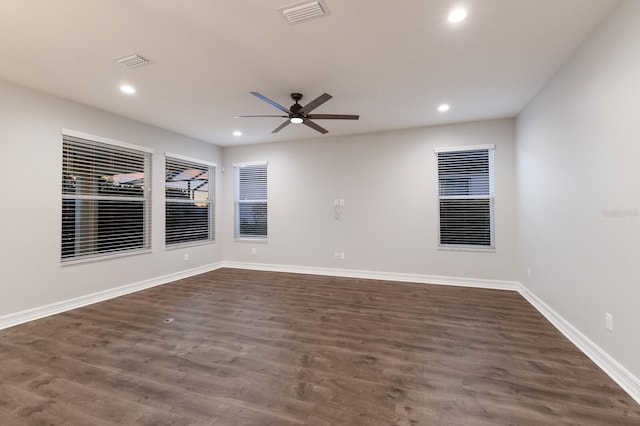 spare room featuring dark wood finished floors, visible vents, and baseboards