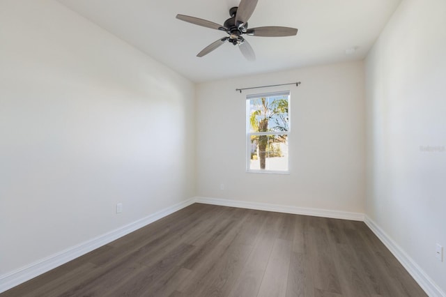 unfurnished room featuring a ceiling fan, baseboards, and dark wood-type flooring