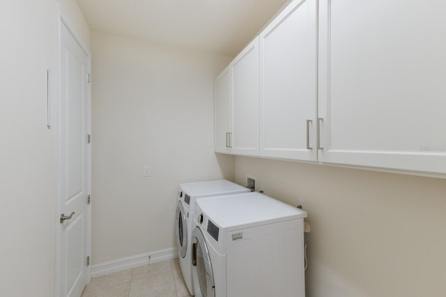 clothes washing area with washer and dryer, cabinet space, baseboards, and light tile patterned flooring