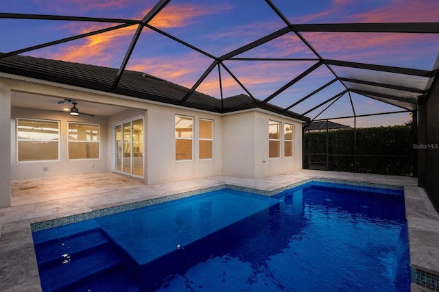 outdoor pool with glass enclosure, a patio area, and a ceiling fan