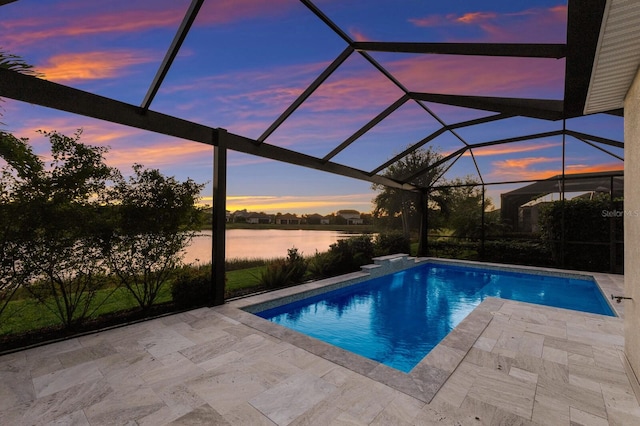 outdoor pool featuring glass enclosure, a patio, and a water view