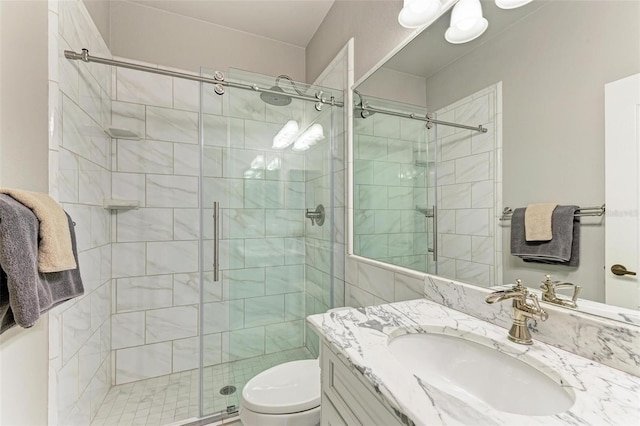 bathroom featuring a shower with door, vanity, and toilet