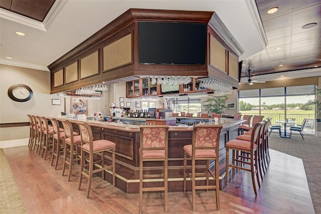 bar featuring hardwood / wood-style floors, ceiling fan, and crown molding