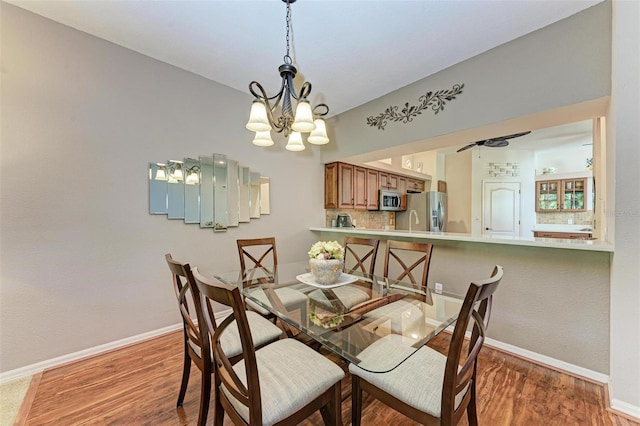 dining room with hardwood / wood-style flooring and ceiling fan with notable chandelier