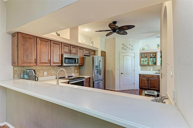 kitchen featuring ceiling fan, wood-type flooring, backsplash, and appliances with stainless steel finishes