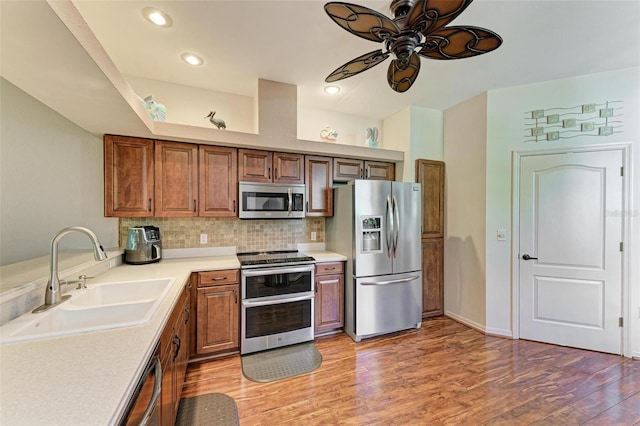 kitchen with decorative backsplash, stainless steel appliances, ceiling fan, sink, and hardwood / wood-style floors