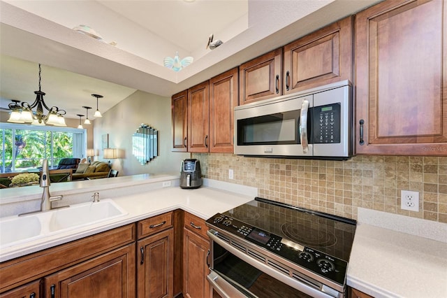 kitchen with backsplash, stainless steel appliances, sink, pendant lighting, and a chandelier