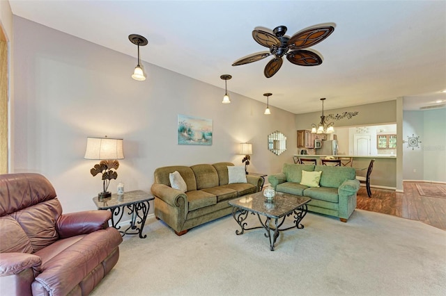 living room with ceiling fan with notable chandelier and light hardwood / wood-style floors