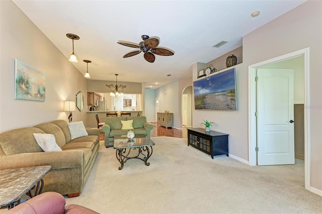 living room with ceiling fan with notable chandelier and light colored carpet