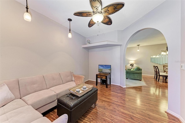 living room with ceiling fan with notable chandelier, wood-type flooring, and vaulted ceiling