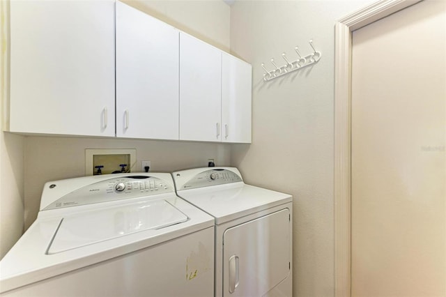 clothes washing area with cabinets and washing machine and clothes dryer