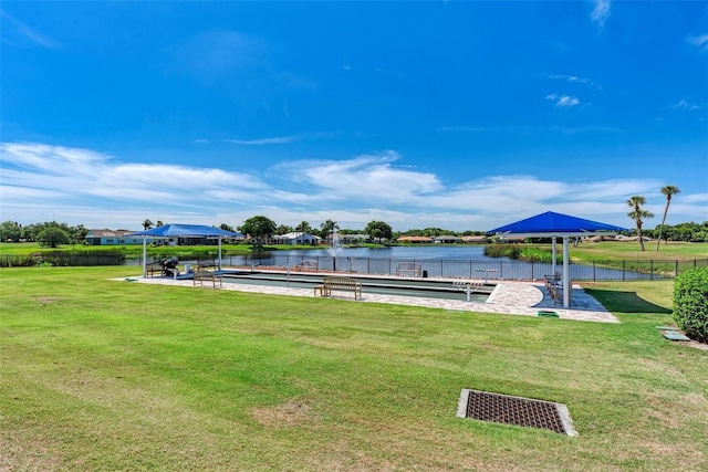 view of community with a water view, a dock, and a lawn