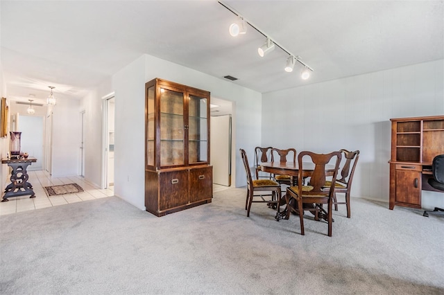 carpeted dining area featuring track lighting