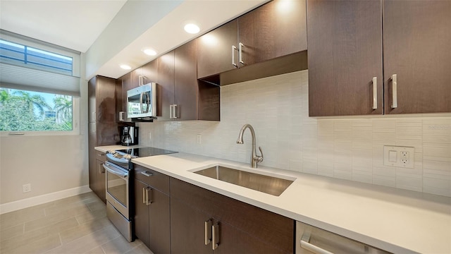 kitchen featuring decorative backsplash, appliances with stainless steel finishes, dark brown cabinetry, and sink