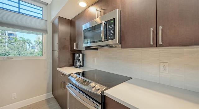 kitchen with appliances with stainless steel finishes, dark brown cabinets, tasteful backsplash, and a wealth of natural light