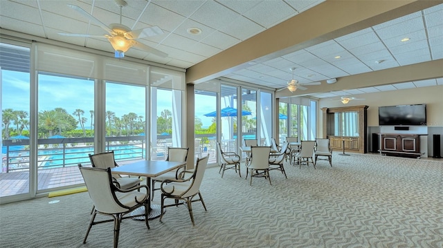 sunroom with ceiling fan, plenty of natural light, and beamed ceiling