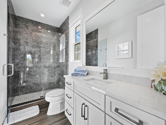 bathroom with hardwood / wood-style floors, vanity, toilet, and a shower with door