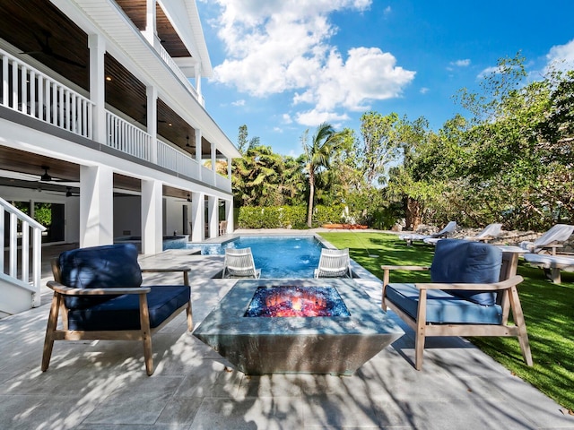 view of pool featuring a patio area, ceiling fan, a yard, and a fire pit