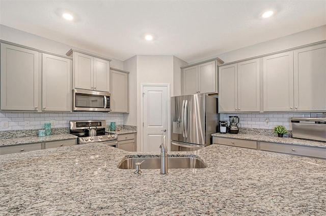 kitchen featuring light stone countertops, sink, and appliances with stainless steel finishes