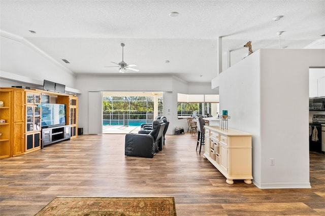 living room with ornamental molding, a textured ceiling, ceiling fan, wood-type flooring, and lofted ceiling