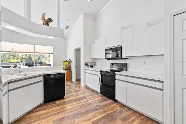 kitchen featuring black appliances, white cabinetry, sink, and hardwood / wood-style floors