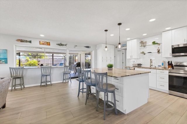 kitchen featuring white cabinets, a kitchen island, light stone counters, and stainless steel appliances