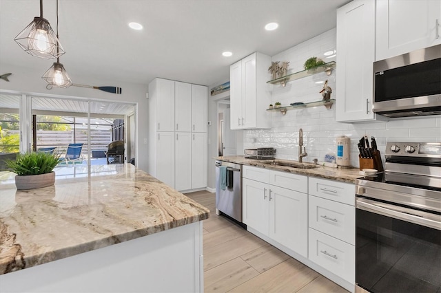 kitchen featuring stainless steel appliances, sink, light hardwood / wood-style floors, white cabinetry, and hanging light fixtures