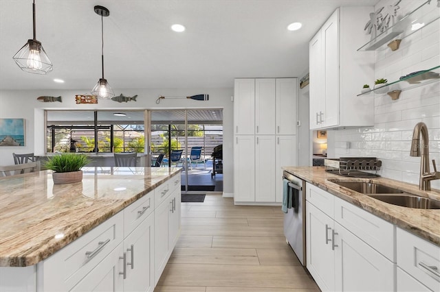 kitchen with light stone countertops, sink, light hardwood / wood-style flooring, stainless steel dishwasher, and white cabinets