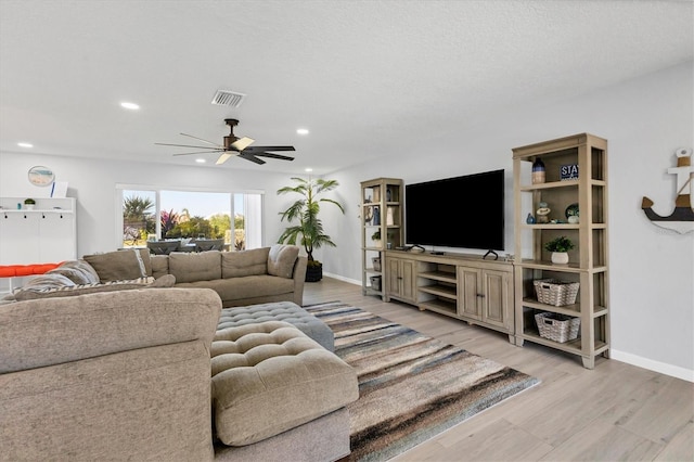 living room featuring wood-type flooring, a textured ceiling, and ceiling fan