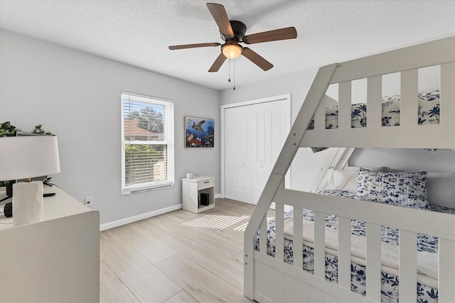 bedroom featuring a textured ceiling, a closet, ceiling fan, and light hardwood / wood-style floors