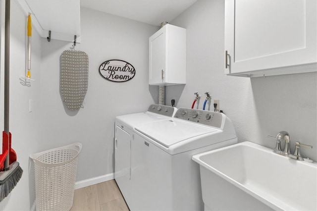 laundry area with cabinets, light hardwood / wood-style floors, washing machine and clothes dryer, and sink