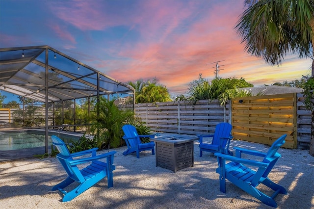 patio terrace at dusk featuring a lanai and an outdoor fire pit