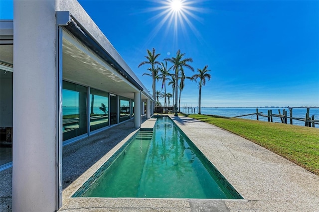 view of swimming pool with a lawn, a dock, and a water view