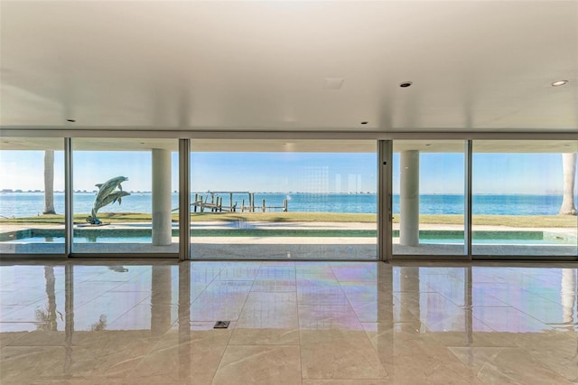 interior space featuring a water view, floor to ceiling windows, and a healthy amount of sunlight