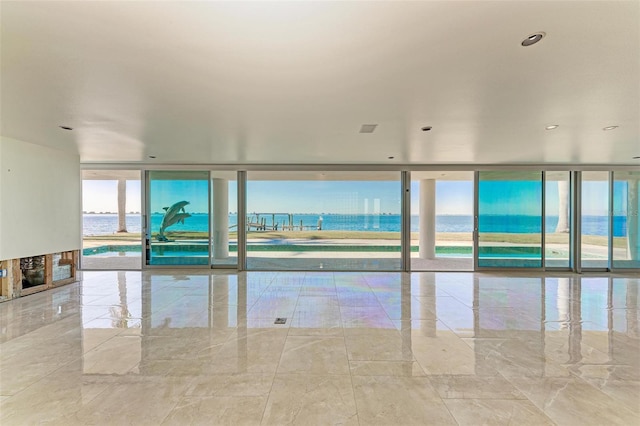 unfurnished room with floor to ceiling windows and a water view