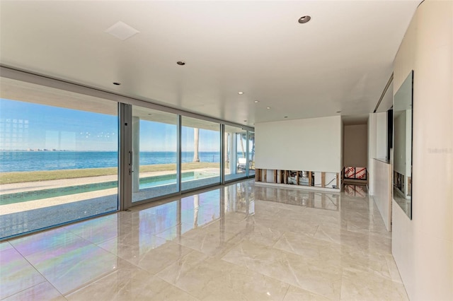 spare room featuring a water view and expansive windows