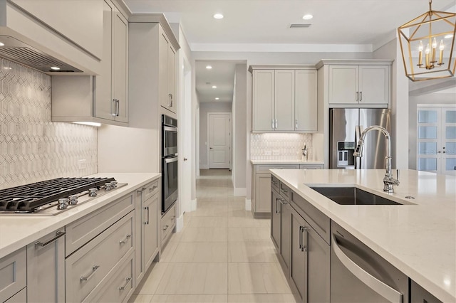 kitchen featuring gray cabinetry, sink, appliances with stainless steel finishes, decorative light fixtures, and custom range hood