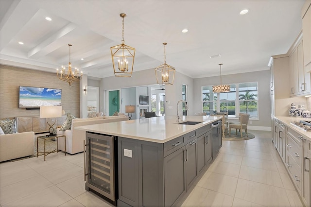 kitchen with gray cabinetry, pendant lighting, a kitchen island with sink, sink, and beverage cooler