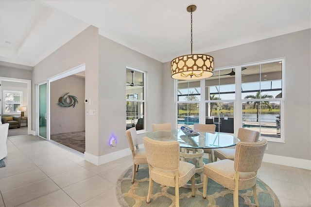 tiled dining room featuring ceiling fan and a water view