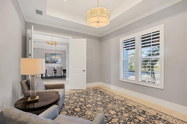 living area with a tray ceiling and a notable chandelier