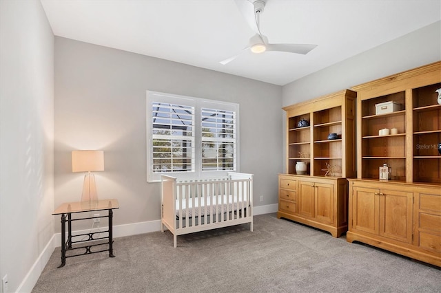 carpeted bedroom with ceiling fan and a crib