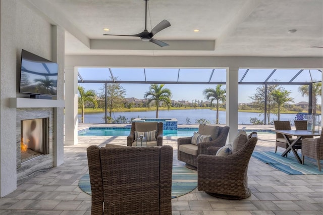 view of patio featuring an outdoor living space with a fireplace, a water view, ceiling fan, and a lanai