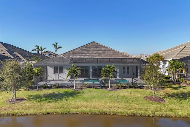 rear view of property with glass enclosure, a patio area, a yard, and a water view